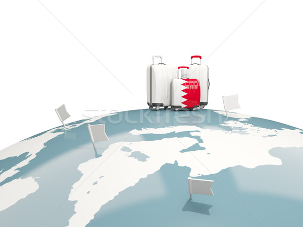 Luggage with flag of bahrain. Three bags on top of globe Stock photo © MikhailMishchenko