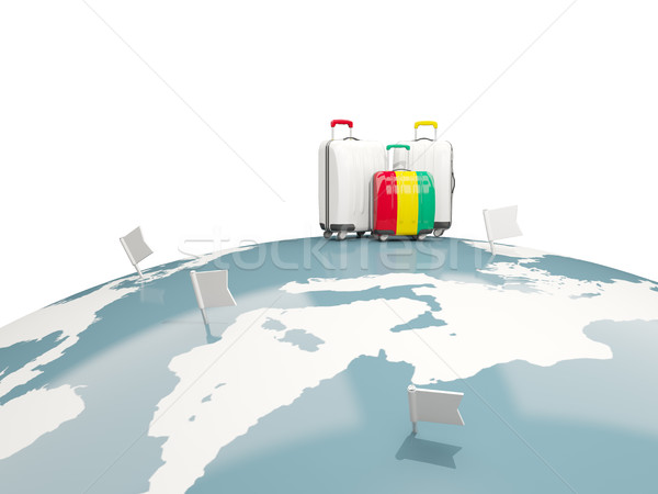 Luggage with flag of guinea. Three bags on top of globe Stock photo © MikhailMishchenko
