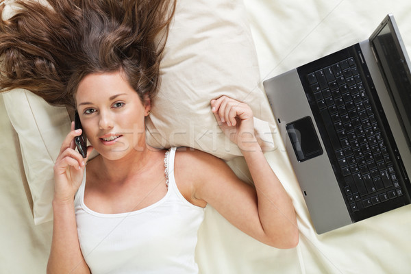 Fiatal nő ágy telefon laptop ruhátlanul beszél Stock fotó © MikLav
