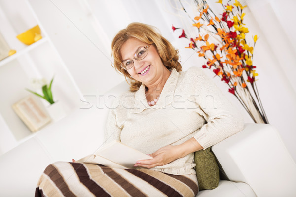 Senior mulher sessão sala de estar leitura livro Foto stock © MilanMarkovic78