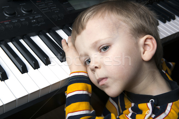 Stock photo: dreaming little boy sitting at the piano