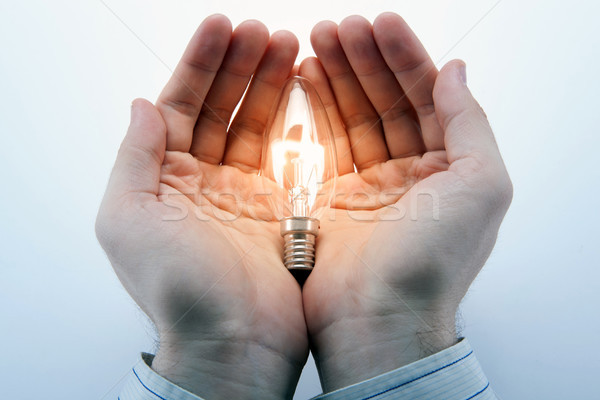 Men's hands hold a burning light bulb and the symbol of the idea Stock photo © mizar_21984