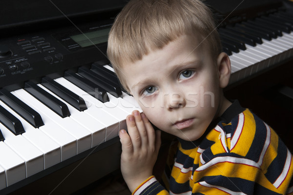 Stock photo: dreaming little boy sitting at the piano