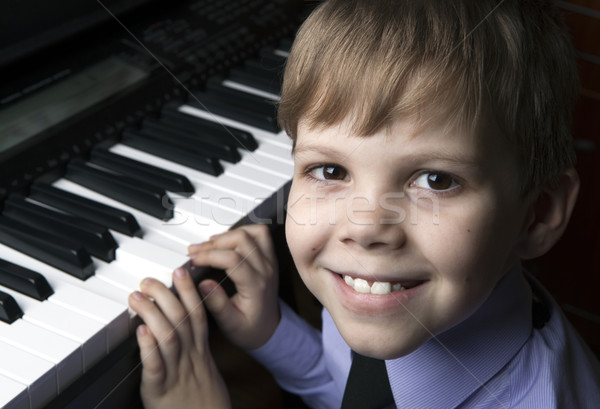 Stock photo: smiling little boy sitting at the piano