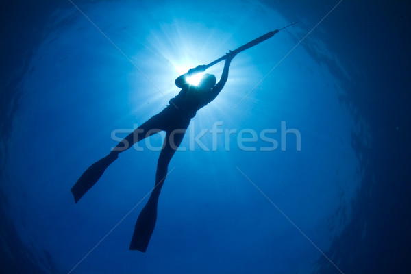 Stock photo: A silhouette of a young woman spearfishing