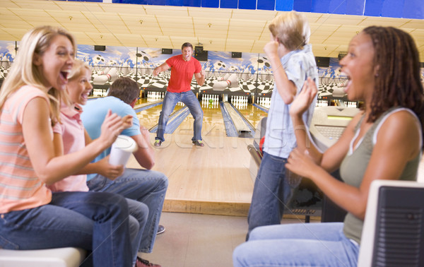 Family in bowling alley with two friends cheering and smiling Stock photo © monkey_business