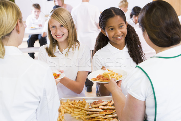 Lunchladies serving plates of lunch in school cafeteria Stock photo © monkey_business
