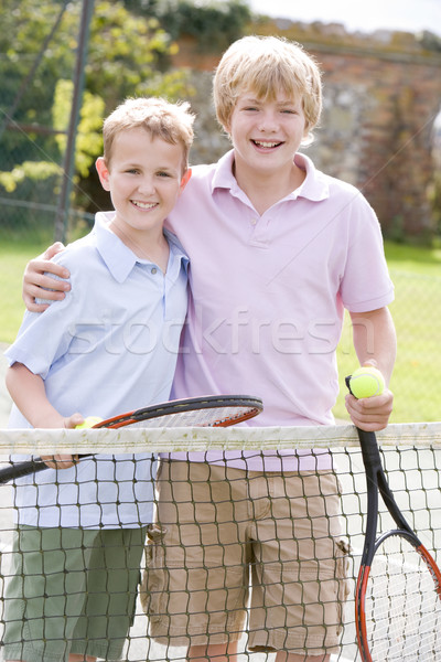 Stock photo: Two young male friends with rackets on tennis court smiling