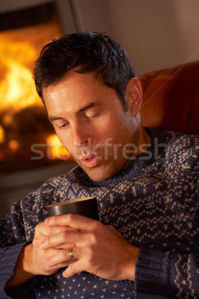 Middle Aged Man Relaxing With Hot Drink By Cosy Log Fire Stock photo © monkey_business