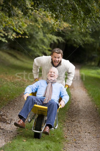 Grown up son pushing father in wheelbarrow Stock photo © monkey_business