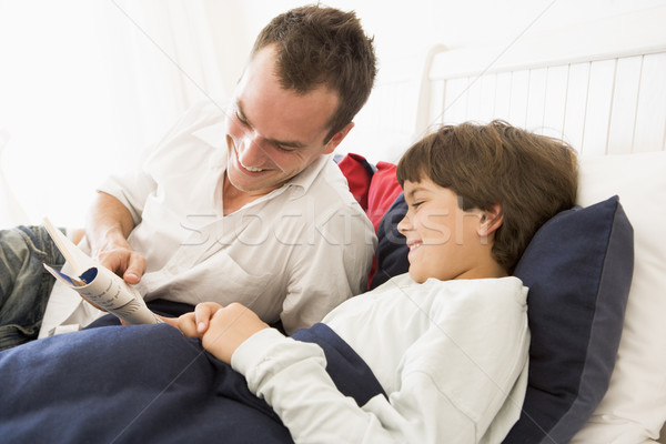Man reading book to young boy in bed smiling Stock photo © monkey_business