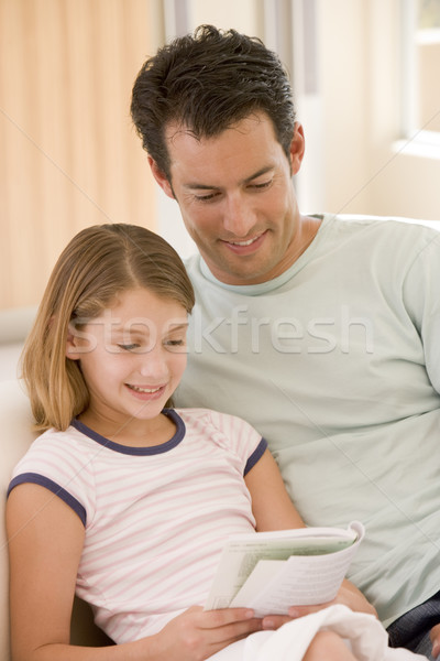 Stock photo: Man and young girl in living room reading book and smiling