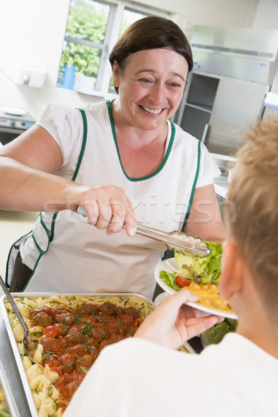 Lunchlady serving plate of lunch in school cafeteria Stock photo © monkey_business