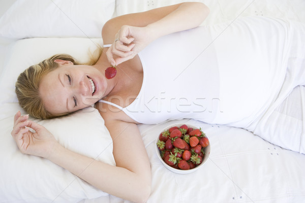 Mulher grávida cama tigela morangos sorridente feliz Foto stock © monkey_business