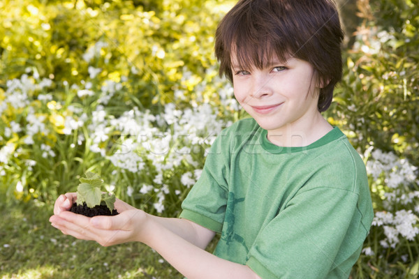 Stock photo: Young boy outdoors holding plant smiling
