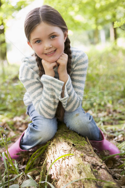 Young girl outdoors in woods sitting on log smiling Stock photo © monkey_business