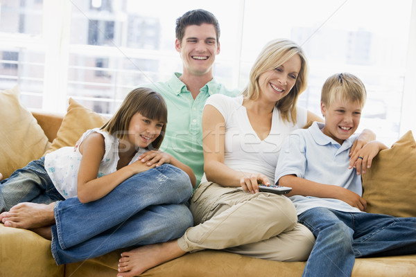 Family sitting in living room with remote control smiling Stock photo © monkey_business