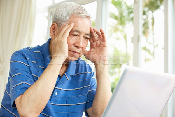 Worried Senior Chinese Man Sitting At Desk Using Laptop At Home Stock photo © monkey_business