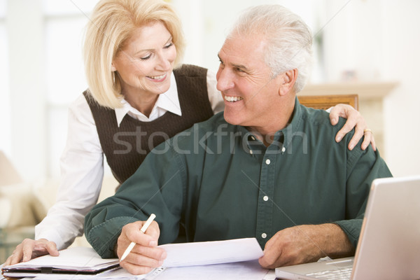 Couple in dining room with laptop and paperwork smiling Stock photo © monkey_business