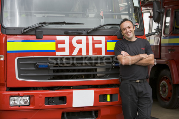 Stock photo: Portrait of a firefighter standing by a fire engine