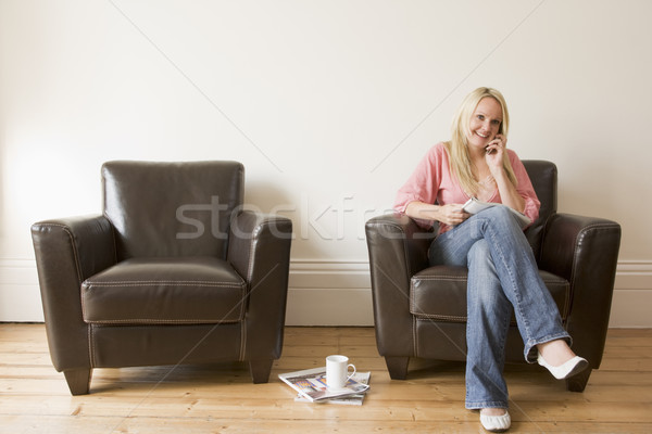 Femeie şedinţei scaun revistă telefon celular femeie zambitoare Imagine de stoc © monkey_business