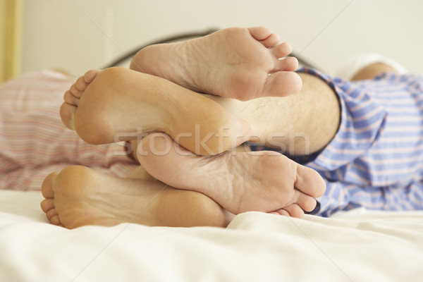 Stock photo: Close Up Of Couple's Feet Relaxing On Bed At Home