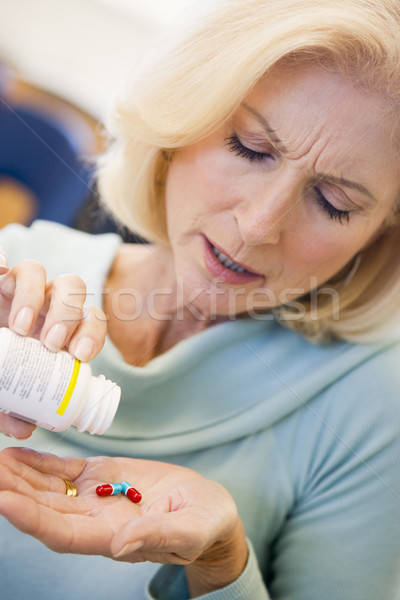 Stock photo: Senior Woman Pouring Pills Out Of Bottle