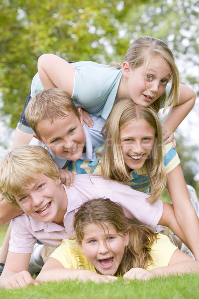 Five young friends piled on each other outdoors smiling Stock photo © monkey_business