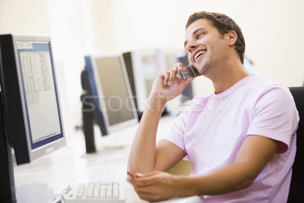 Man sitting in computer room using cellular phone and smiling Stock photo © monkey_business
