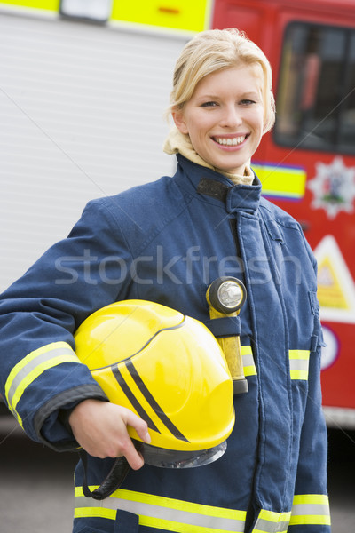 Stock photo: Portrait of a firefighter standing in front of a fire engine
