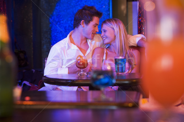 Happy young couple sitting in a nightclub, smiling at each other Stock photo © monkey_business
