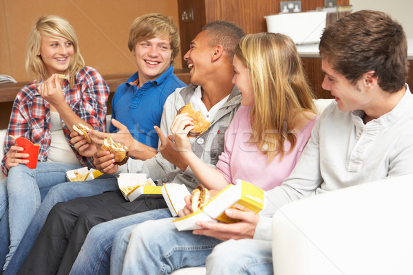 Group Of Teenage Friends Sitting On Sofa At Home Eating Fast Foo Stock photo © monkey_business