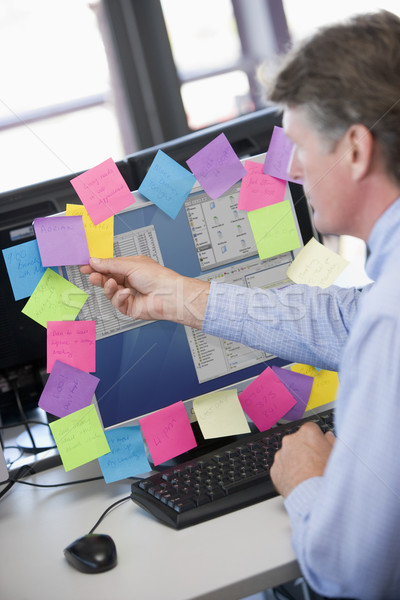 Stock photo: Businessman in office at monitor with notes on it