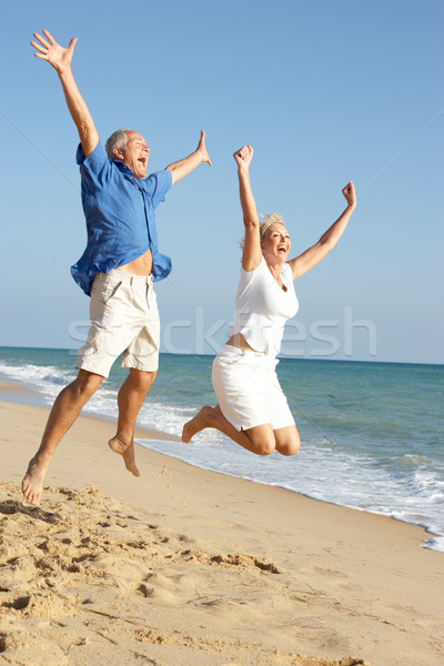 Senior Couple Enjoying Beach Holiday Jumping In Air Stock photo © monkey_business