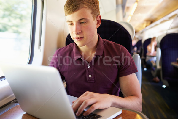 Moço usando laptop trem jornada computador feliz Foto stock © monkey_business
