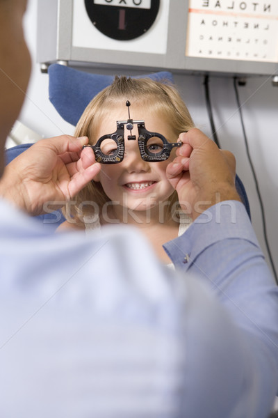 Optometrist in exam room with young girl in chair smiling Stock photo © monkey_business