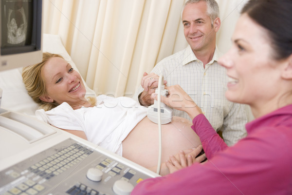 Stock photo: Pregnant woman getting ultrasound from doctor with husband watch