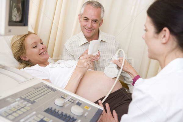 Stock photo: Pregnant woman getting ultrasound from doctor with husband looki