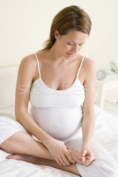 Pregnant woman sitting in bed rubbing feet Stock photo © monkey_business