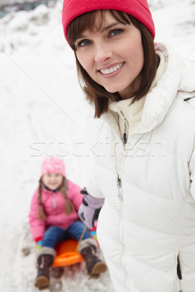 Mother Pulling Daughter On Sledge Along Snowy Street In Ski Reso Stock photo © monkey_business