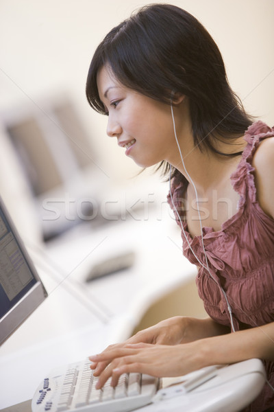 Woman in computer room listening to MP3 player while typing and  Stock photo © monkey_business