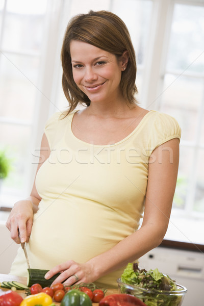 Stock photo: Pregnant woman in kitchen making a salad smiling