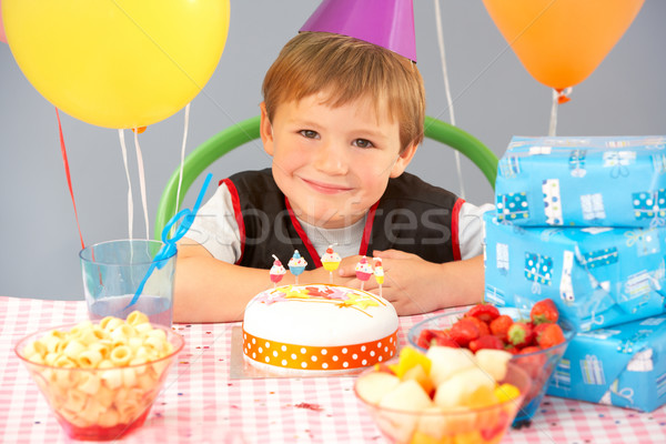 Stock photo: Young boy with birthday cake and gifts at party