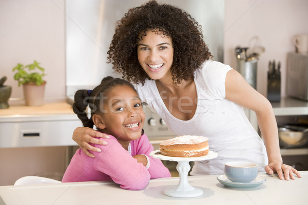 Stock photo: Woman and young girl in kitchen with cake and coffee smiling