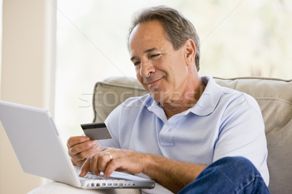 Foto stock: Homem · sala · de · estar · laptop · cartão · de · crédito · sorridente · negócio