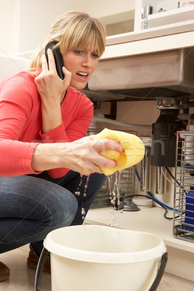 Stock photo: Woman Mopping Up Leaking Sink On Phone To Plumber