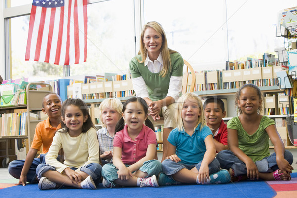 Stock photo: Kindergarten teacher sitting with children in library