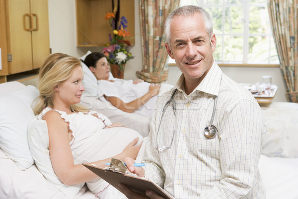 Doctor sitting by pregnant women holding chart and smiling Stock photo © monkey_business
