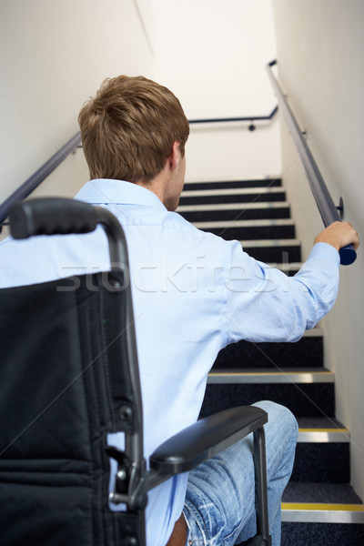 Stock photo: Man in wheelchair at foot of stairs