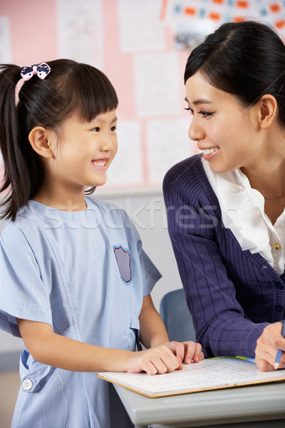 Teacher Helping Student Working At Desk In Chinese School Classr Stock photo © monkey_business
